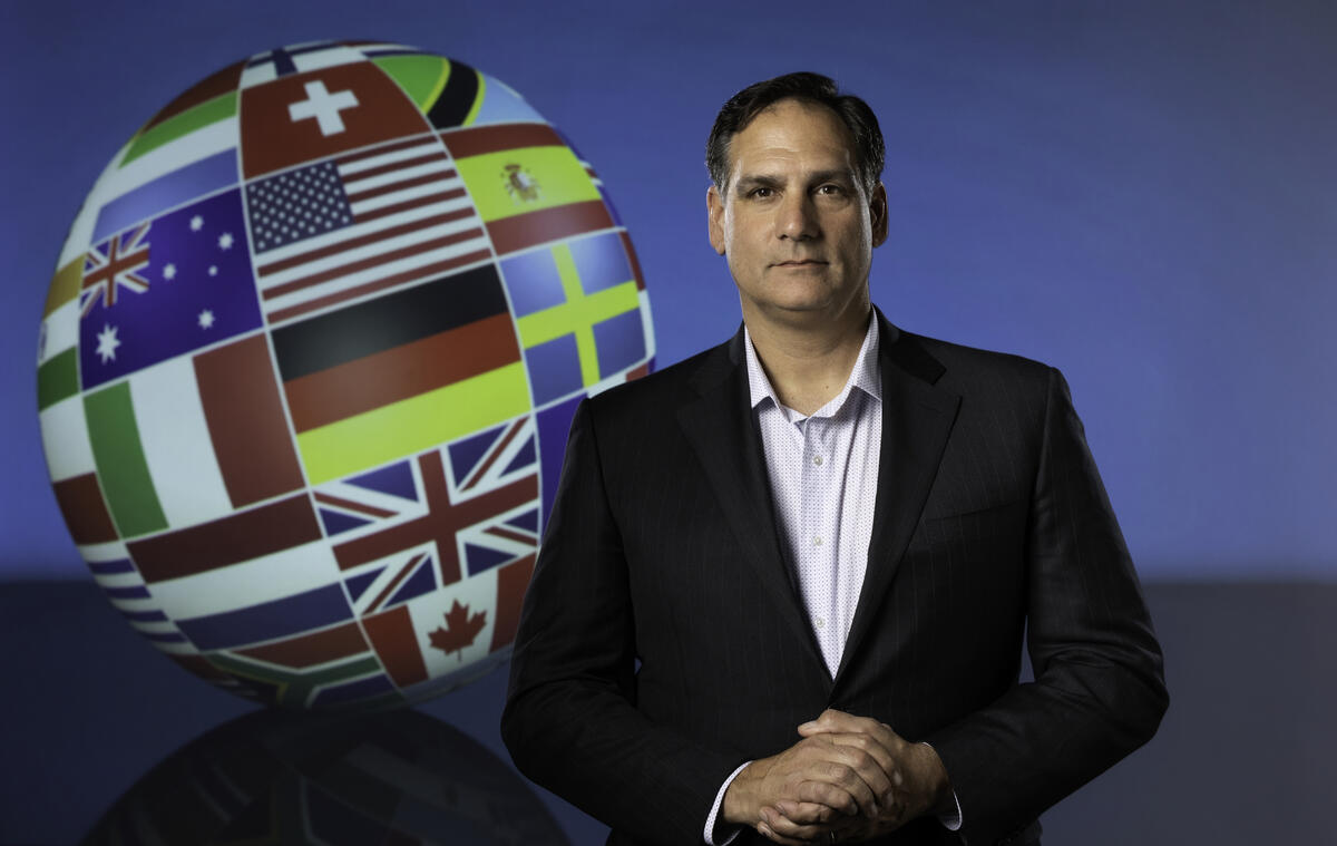 Man standing next to globe covered in different flags