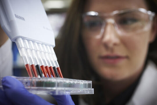 A woman wearing protective googles and holding on vials