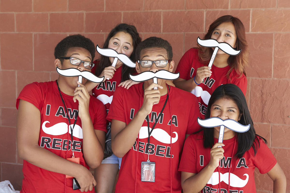 5 students hold paper mustaches in front of face