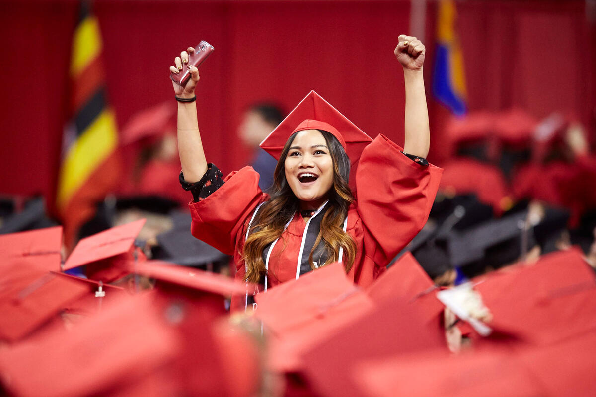 Student arms raised celebrating graduation. 