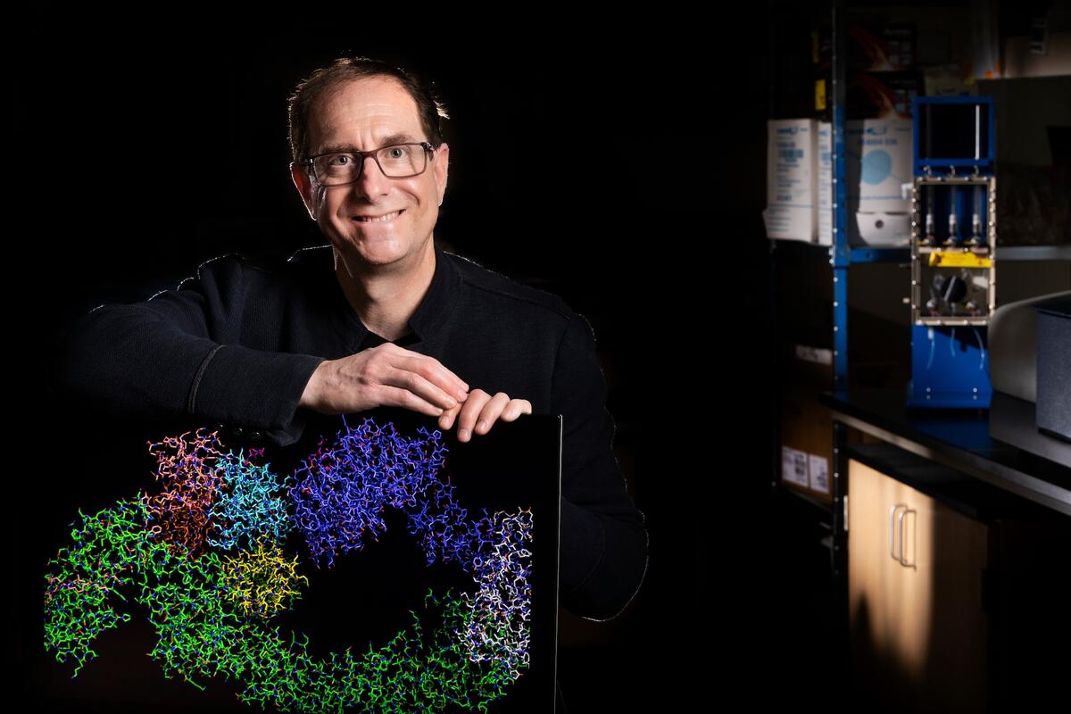 Gary Kleiger sits in his lab with a computer monitor showing a colorful protein complex