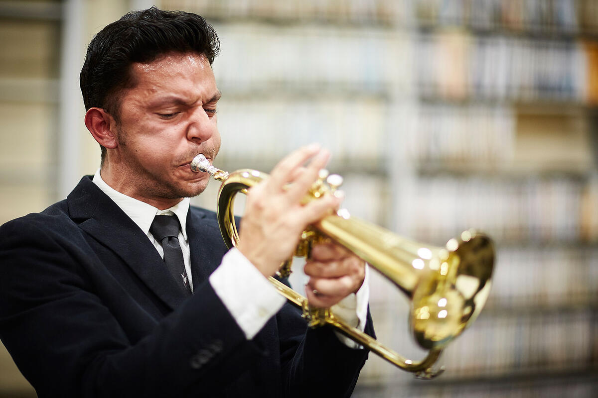 Young man wearing a black suit playing a trumpet