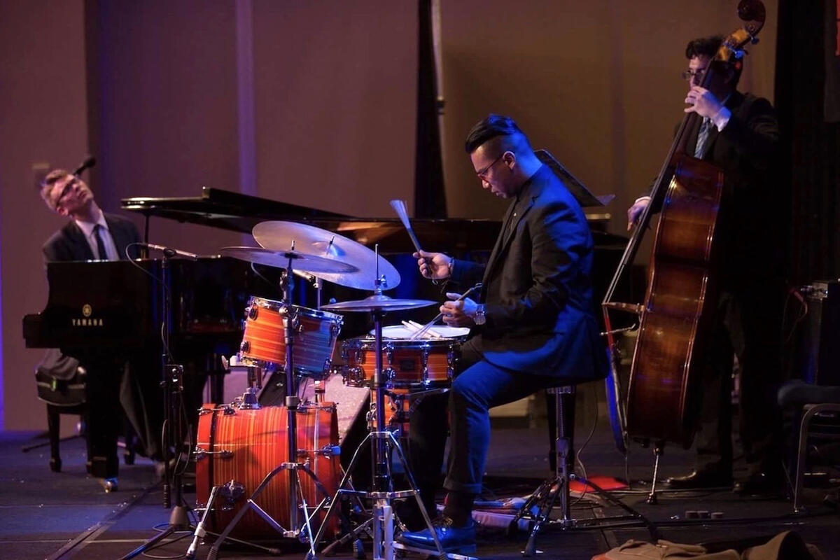 three men playing piano, drums, and bass