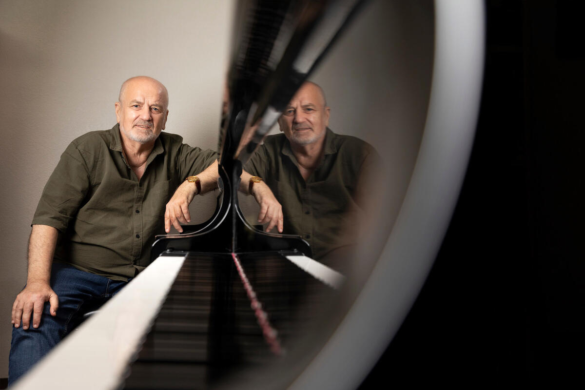 A man sits at the end of a piano