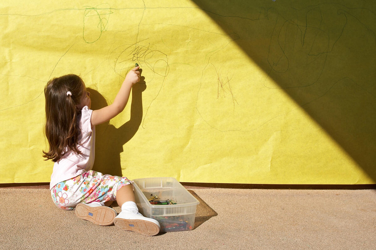 girl coloring on yellow paper