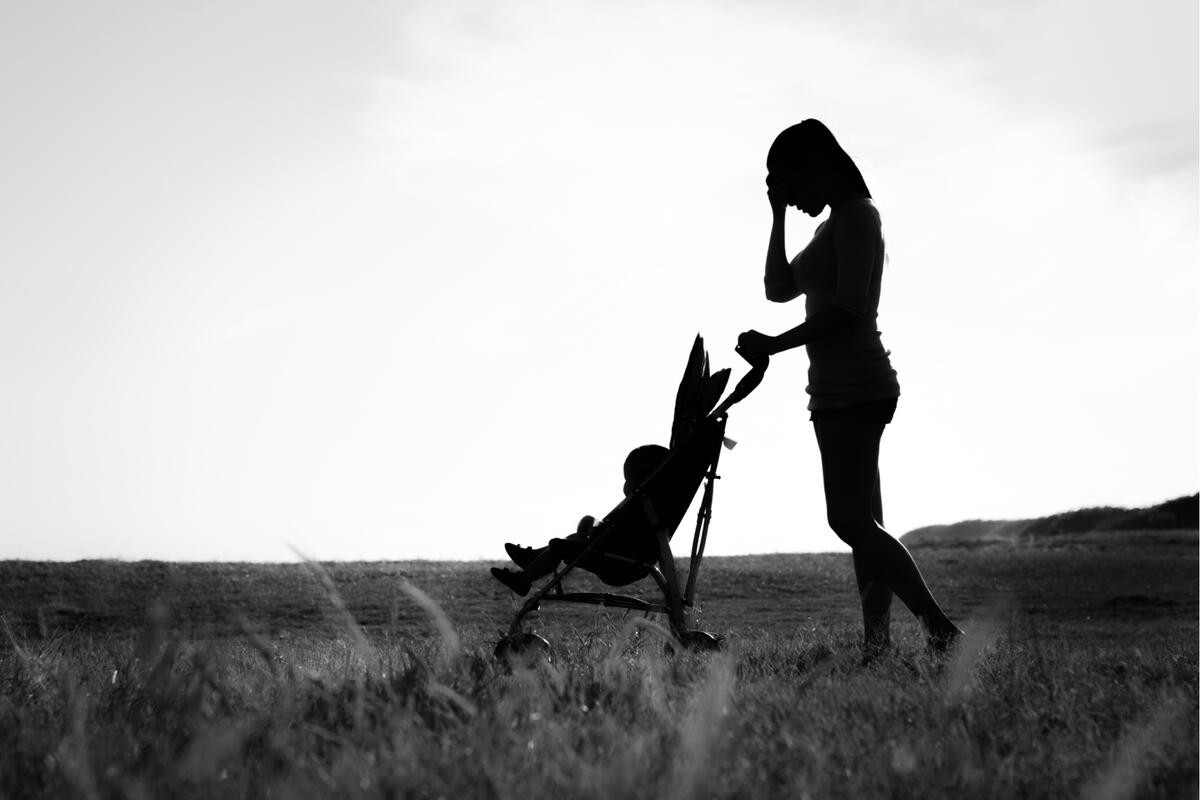 An silhouette image of a mother pushing her child in a stroller.