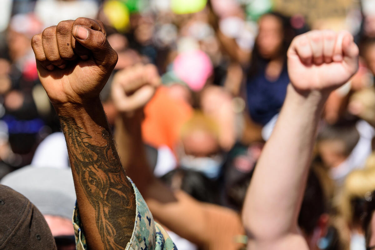 Hands of white and black people being raised in the air at a protest.