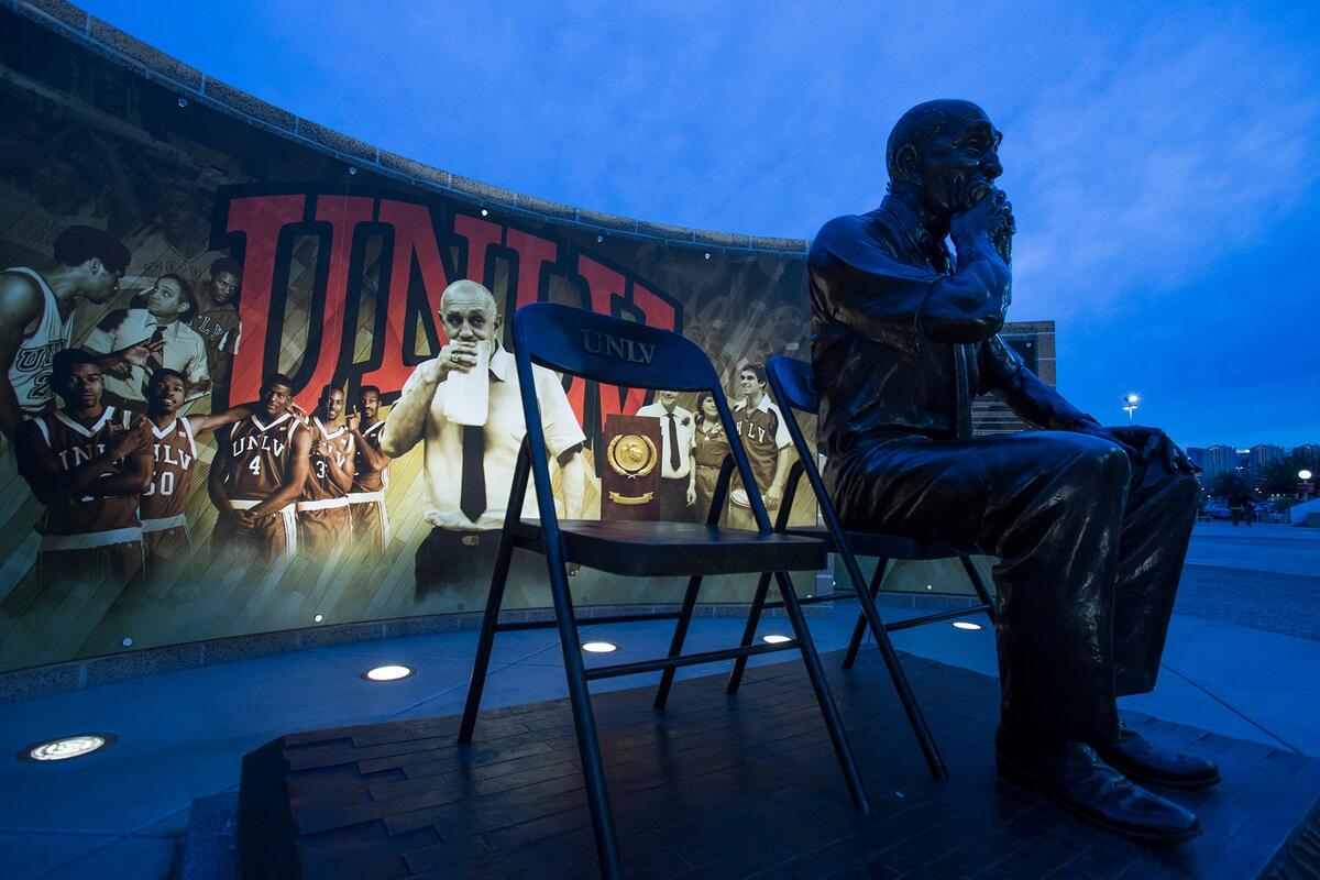 Tarkanian statue at dusk with lighted sign behind