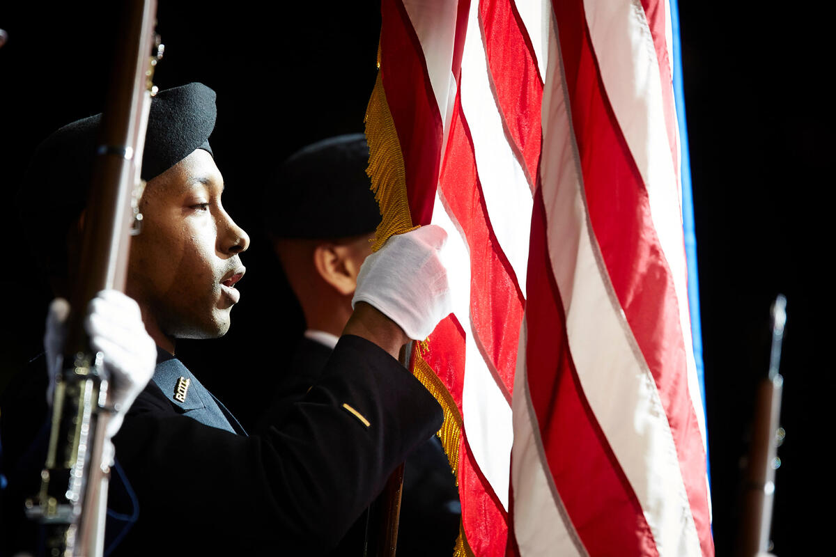 An army R.O.T.C. student in uniform holding the American flag.