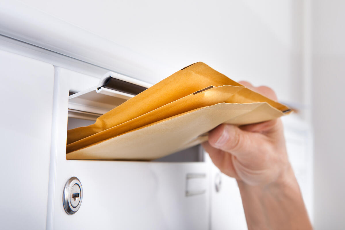 Hand putting mail through a mail slot