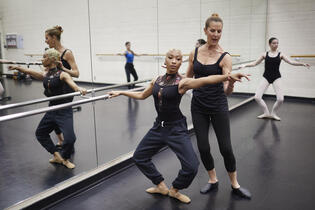 A woman guiding a student in a dance class.