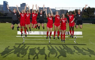 Women's soccer team jumping in the air and smiling