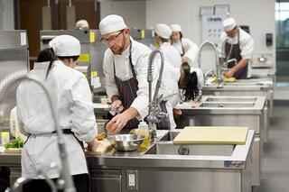 Culinary students work in kitchen