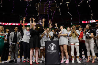 The Lady Rebels team holding up the Mountain West Conference trophy.