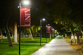 A view of the campus at night, with streetlights illuminating the UNLV pole banners.
