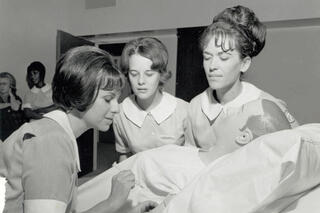 A photo from (likely) the 1960s of three female nurses working on a manikin.