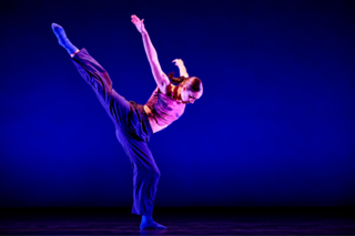 A dancer mid-movement in front of a dark background.