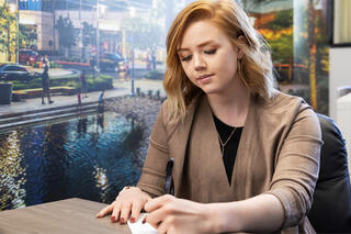 A woman writes notes in front of a wall with a mural of the Las Vegas Strip.
