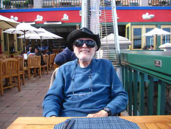 older man with hat and sunglasses sitting at table and smiling