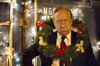 Ebenezer Scrooge with wreath wrapped around neck.