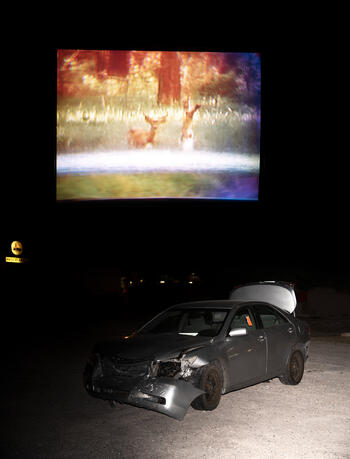 A wrecked car in front of a screen