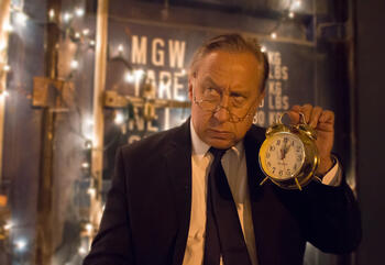 Ebenezer Scrooge holding a clock.