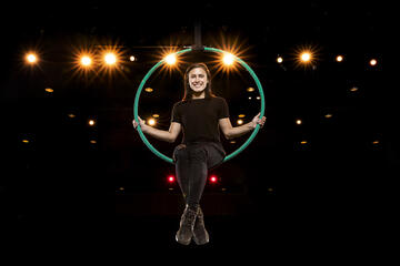 woman sitting in hoop above stage