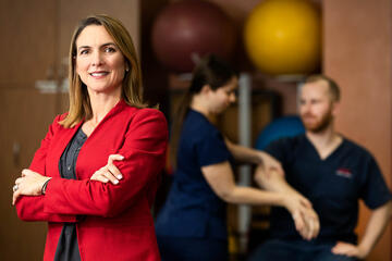 Professor Jennifer Nash poses in front of physical therapy students performing an exam.
