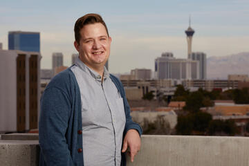 Man on balcony with Las Vegas in the background.