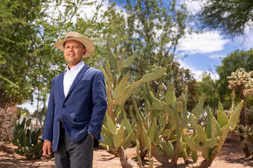 Portrait of Sam Fugazzotto standing in front of cacti
