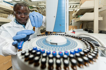 man in lab coat using equipment in a university laboratory