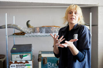 A woman stands in front of historical artifacts