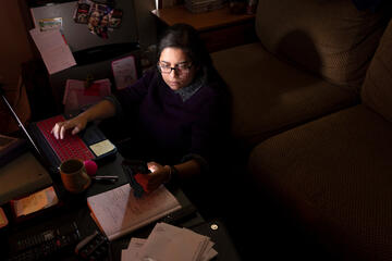 A woman sits at a desk in a dark room