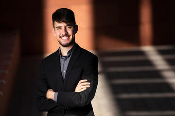 A man stands in front of Greenspun Hall with his arms folded