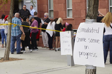 Stands stand behind the police tape of a simulated crime scene