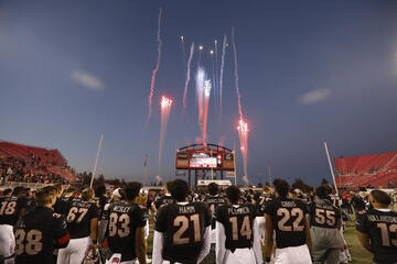 football players look up at fireworks display