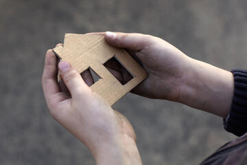 hands holding cardboard cutout of house