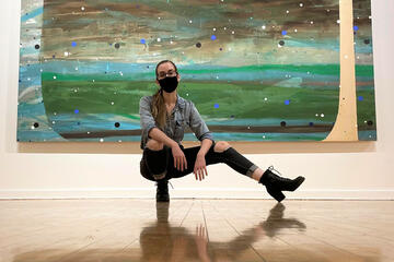 woman in mask in front of large artwork