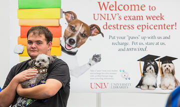 Guy holding puppy in his arms at Paws From Your Studies destress epicenter
