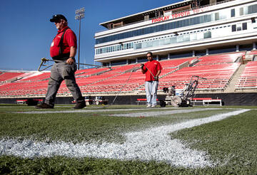 Two workers repainting lines on the at the Sam Boyd Stadium.