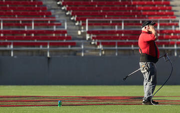Side view of worker standing with paint spray gun held to his side.