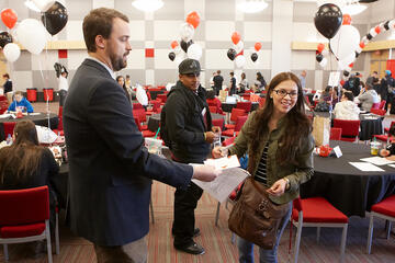 A man handing over papers to a woman.