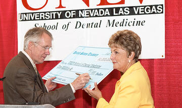 Mrs. Harter standing by Sen. Harry Reid as he signs a giant check.