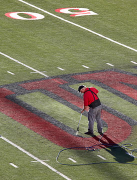 Worker outlining the UNLV logo at the center of the field at the Sam Boyd Stadium