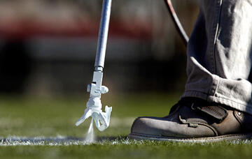 Close up view of the spray gun as it sprays impermanent paint on the field.