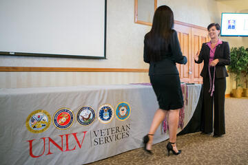 Woman walking in front of the UNLV Veteran Services banner.
