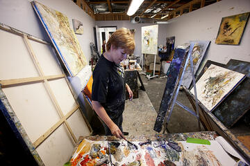 A female painter painting inside of the art studio.