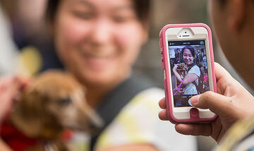 Girl getting a photo taken while holding a dog.