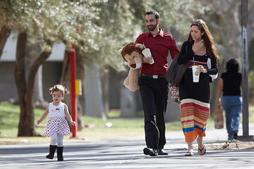 2-year-old Aria Coyle takes the lead as she walks with her stuffed lion-toting father, Daniel, who works on campus, and her mom Tami.
