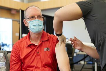 Chris Heavey receives an injection in the arm from a staff member